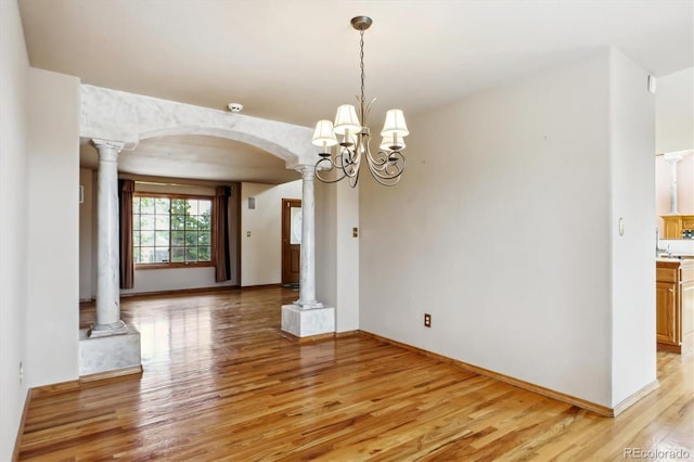 9920 Glenellen Dr, Peyton, CO 80831 - unfurnished dining area featuring baseboards, arched walkways, an inviting chandelier, ornate columns, and light wood finished floors
