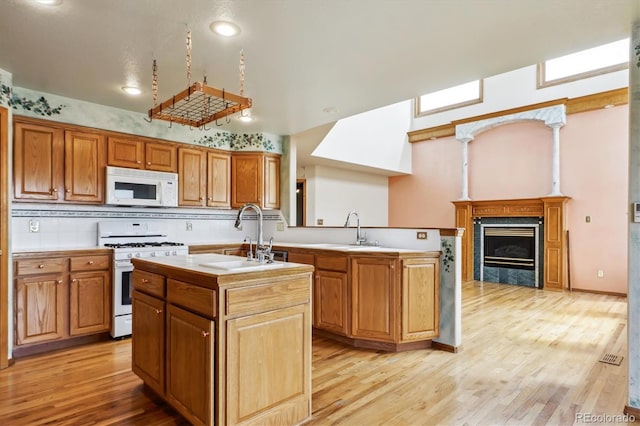 9920 Glenellen Dr, Peyton, CO 80831 - kitchen featuring a sink, an island with sink, white appliances, and light wood finished floors