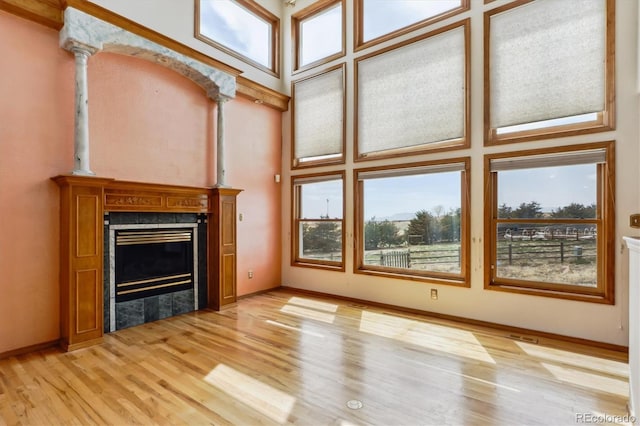 9920 Glenellen Dr, Peyton, CO 80831 - unfurnished living room with light wood-style floors, a tile fireplace, a high ceiling, and baseboards