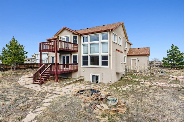 9920 Glenellen Dr, Peyton, CO 80831 - back of property featuring a deck, roof with shingles, stucco siding, and fence