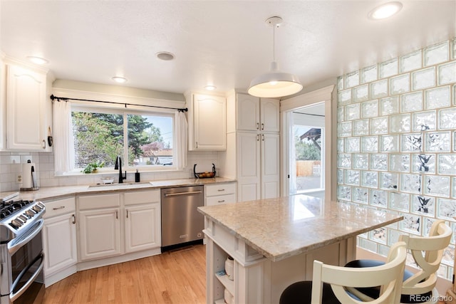 6192 S Pennsylvania St, Centennial, CO 80121 - kitchen featuring appliances with stainless steel finishes, light stone counters, decorative backsplash, light wood-style flooring, and white cabinetry