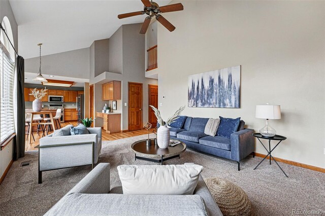 9515 Dolton Way, Highlands Ranch, CO 80126 - living room with high vaulted ceiling, a ceiling fan, baseboards, and light colored carpet