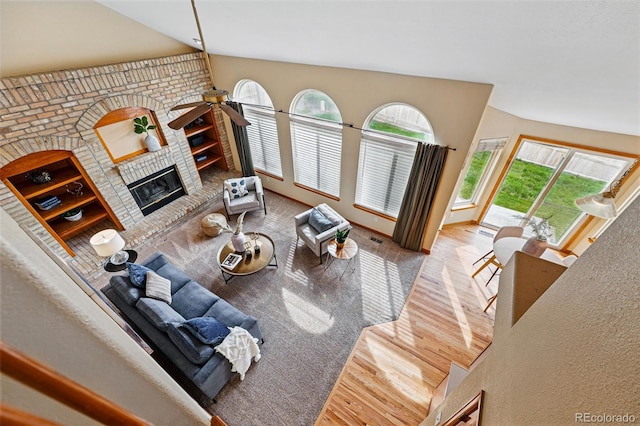 9515 Dolton Way, Highlands Ranch, CO 80126 - living area with wood finished floors, a brick fireplace, vaulted ceiling, and a ceiling fan