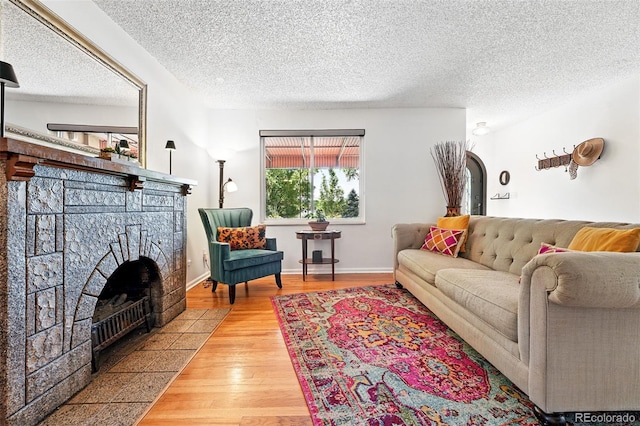 1332 Ash St, Denver, CO 80220 - living area featuring a stone fireplace, wood finished floors, and a textured ceiling