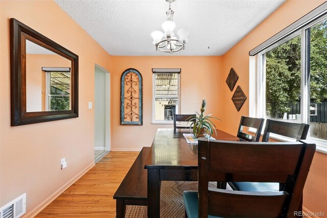 1332 Ash St, Denver, CO 80220 - dining room featuring a chandelier, light wood finished floors, and a textured ceiling