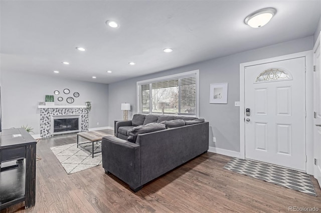 living area featuring wood finished floors, baseboards, a tile fireplace, and recessed lighting