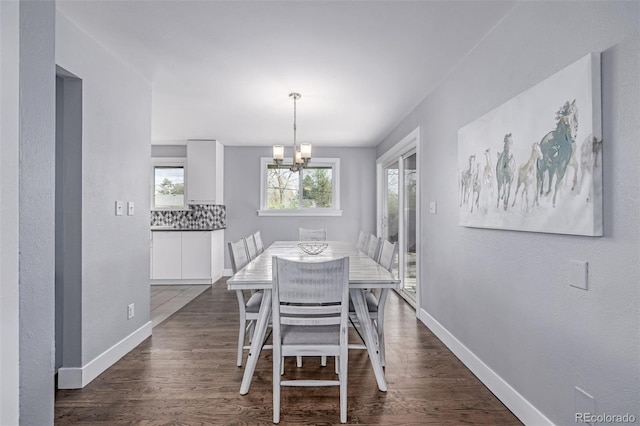 dining room with a chandelier, baseboards, and dark wood-style floors