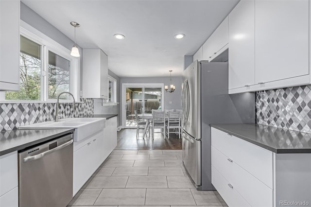 kitchen featuring stainless steel dishwasher, white cabinetry, recessed lighting, decorative backsplash, and pendant lighting