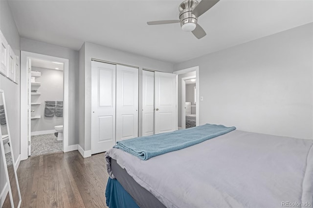 bedroom featuring multiple closets, dark wood-style flooring, baseboards, ensuite bath, and ceiling fan
