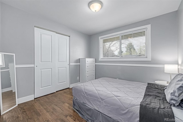 bedroom featuring dark wood-type flooring, a closet, and baseboards