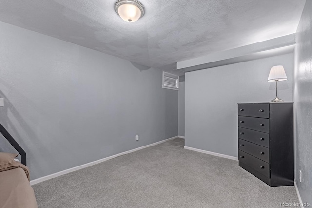 finished below grade area with carpet flooring, a textured ceiling, and baseboards