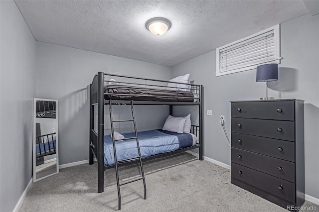 bedroom featuring a textured ceiling, carpet, and baseboards