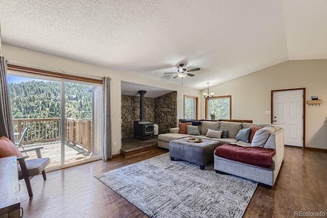 living room featuring lofted ceiling, a textured ceiling, wood finished floors, and a wood stove