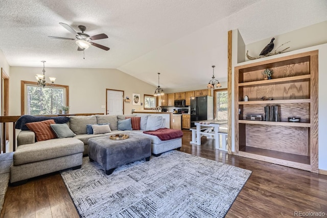 living area featuring vaulted ceiling, dark wood-type flooring, a textured ceiling, and ceiling fan with notable chandelier