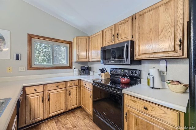 kitchen with lofted ceiling, black range with electric stovetop, light wood-style floors, light countertops, and stainless steel microwave