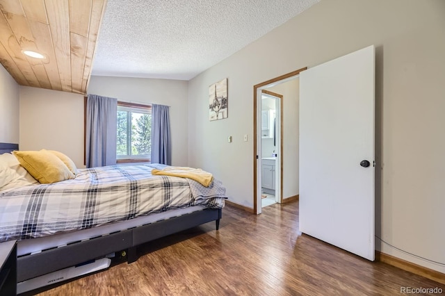 bedroom with a textured ceiling, wood finished floors, and baseboards