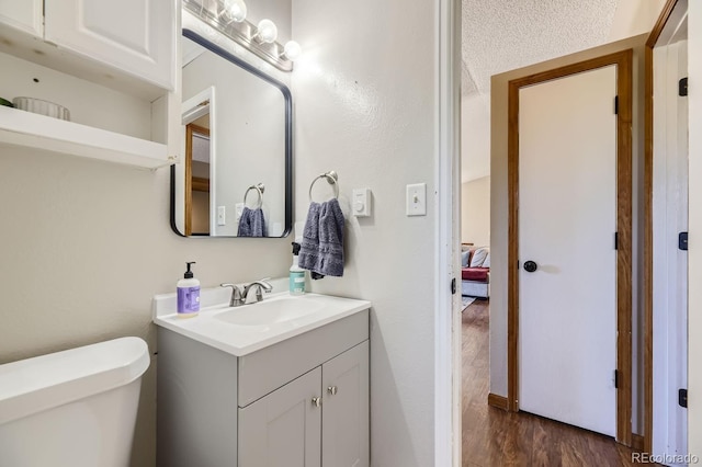 half bathroom featuring vanity, toilet, and wood finished floors