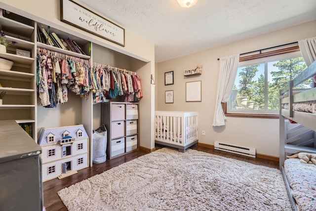 bedroom with a textured ceiling, baseboards, a closet, baseboard heating, and dark wood finished floors