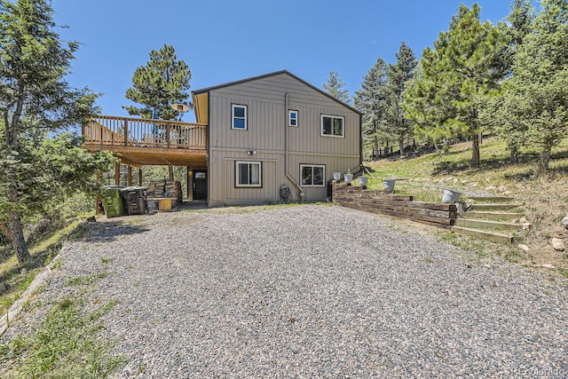 rear view of house featuring driveway and a wooden deck