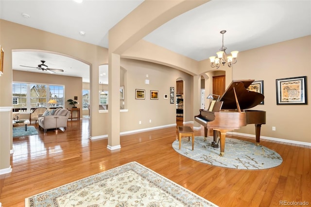 misc room with ceiling fan with notable chandelier and light hardwood / wood-style floors