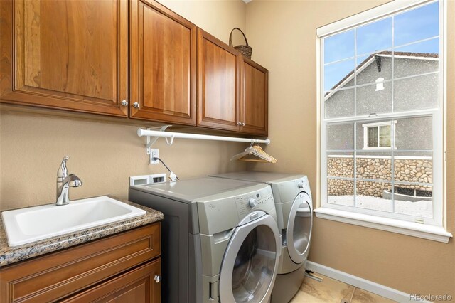 laundry area with cabinets, separate washer and dryer, light tile patterned floors, and sink