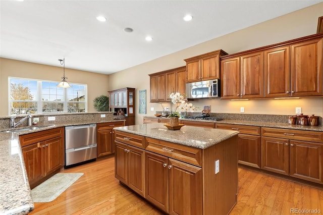 kitchen featuring light hardwood / wood-style floors, sink, appliances with stainless steel finishes, a center island, and pendant lighting