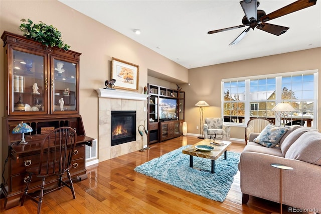 living room with a tiled fireplace, hardwood / wood-style flooring, and ceiling fan