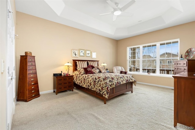 carpeted bedroom with ceiling fan and a raised ceiling