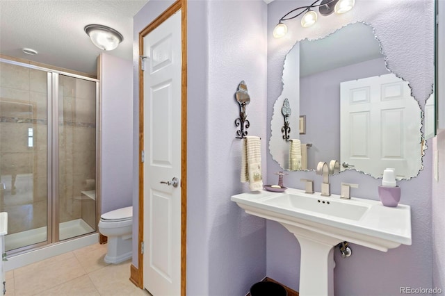 bathroom featuring a shower with door, tile patterned floors, toilet, and a textured ceiling