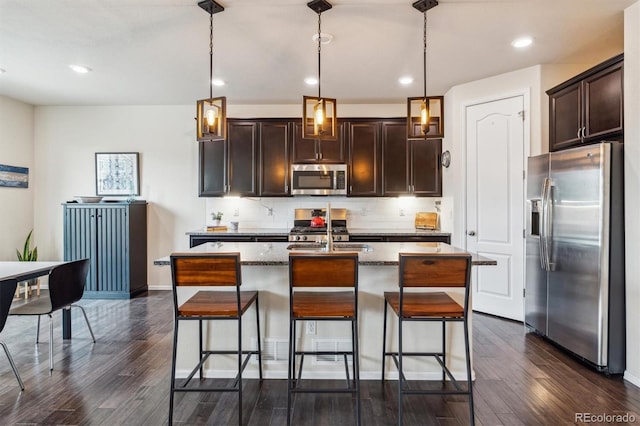 kitchen with a kitchen island with sink, sink, decorative light fixtures, and stainless steel appliances