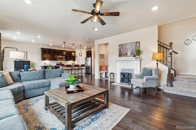 living room featuring dark wood-type flooring, ceiling fan, and a fireplace