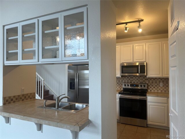 3854 S Dayton Way Unit 308, Aurora, CO 80014 - kitchen with stainless steel appliances, a sink, glass insert cabinets, and tasteful backsplash