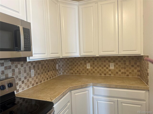 3854 S Dayton Way Unit 308, Aurora, CO 80014 - kitchen featuring stainless steel appliances, tasteful backsplash, and white cabinets