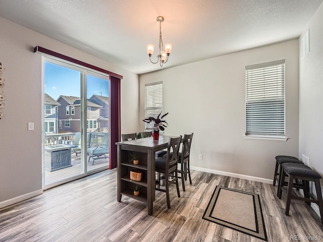 dining area featuring a notable chandelier, hardwood / wood-style flooring, and a textured ceiling