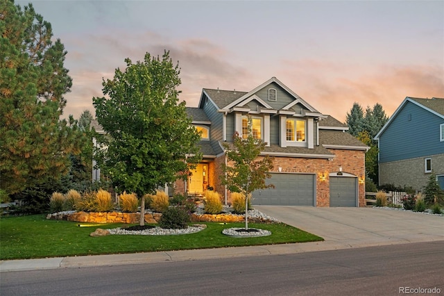 view of front of house featuring brick siding, a shingled roof, a lawn, an attached garage, and driveway