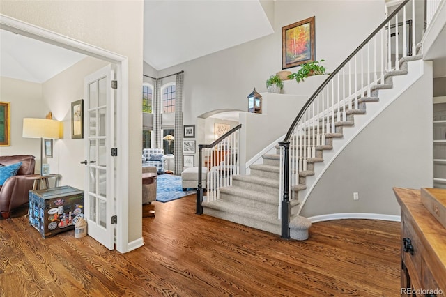 foyer with baseboards, stairs, arched walkways, and wood finished floors