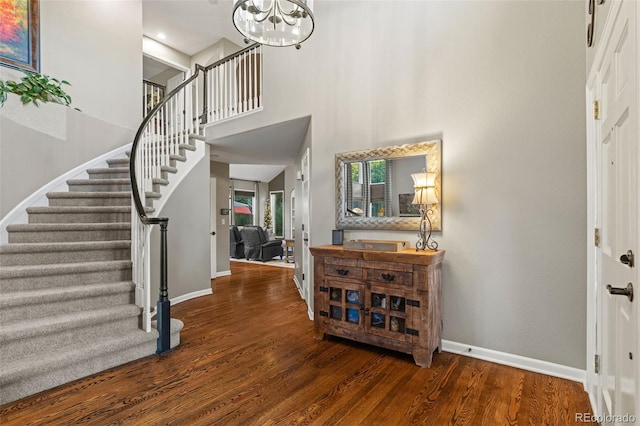 entryway featuring stairs, a towering ceiling, baseboards, and wood finished floors