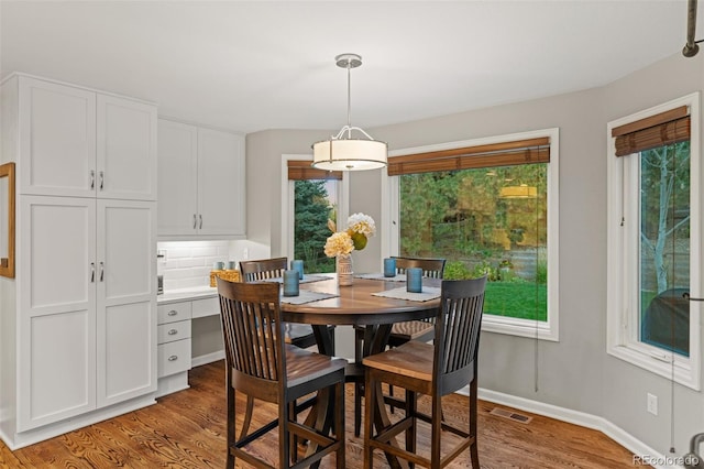 dining area with visible vents, baseboards, and wood finished floors