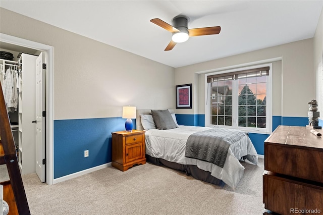 bedroom with a closet, a spacious closet, a ceiling fan, carpet flooring, and baseboards