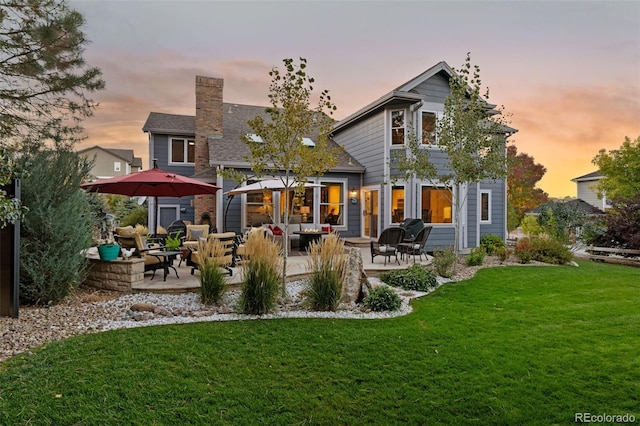 rear view of property with a patio area, a chimney, outdoor lounge area, and a yard