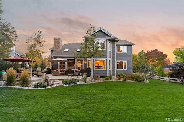 rear view of property featuring an outdoor hangout area, a patio, a lawn, and a chimney