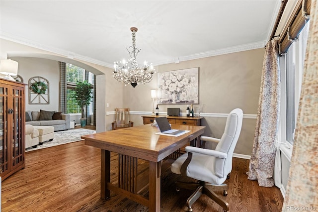 office with arched walkways, wood finished floors, baseboards, ornamental molding, and an inviting chandelier