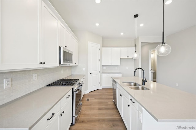 kitchen with stainless steel appliances, sink, a center island with sink, and white cabinets