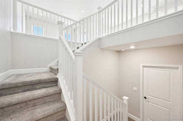 staircase featuring a high ceiling and carpet flooring