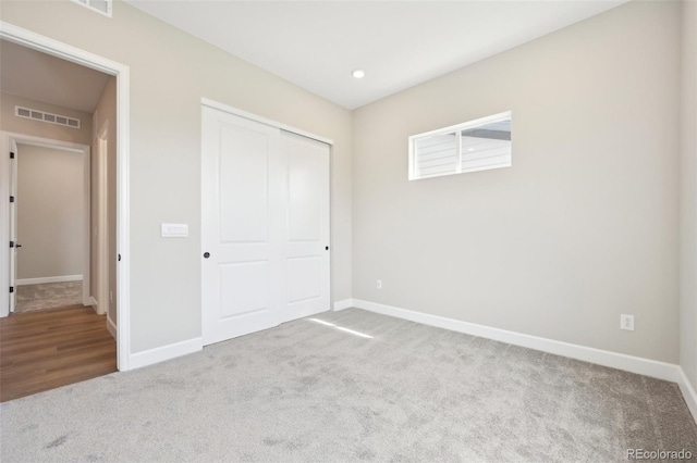 unfurnished bedroom featuring a closet and light carpet