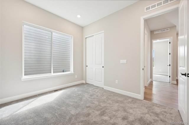 unfurnished bedroom with light colored carpet and a closet