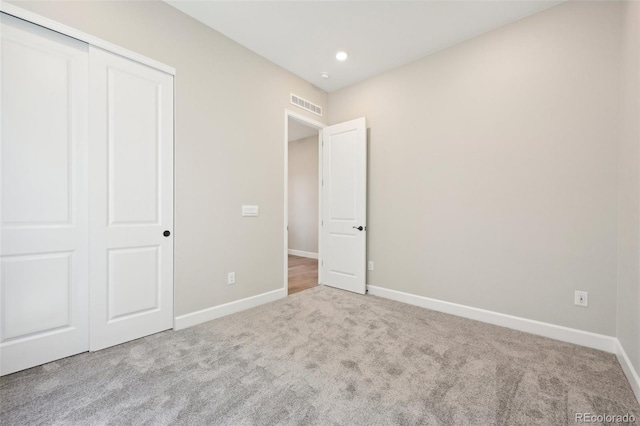 unfurnished bedroom featuring a closet and light carpet