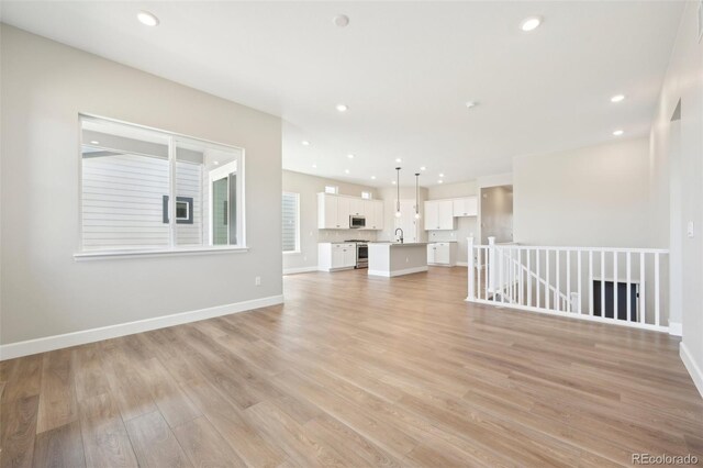 unfurnished living room with sink and light hardwood / wood-style flooring