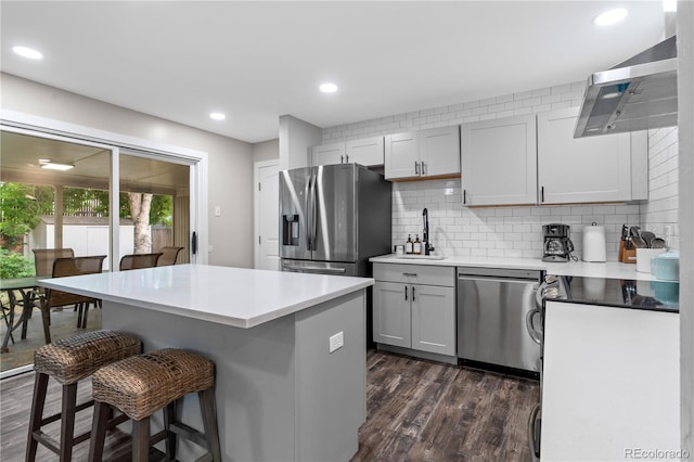 8060 Stuart Pl, Westminster, CO 80031 - kitchen with appliances with stainless steel finishes, wall chimney exhaust hood, a breakfast bar, dark wood-style floors, and decorative backsplash