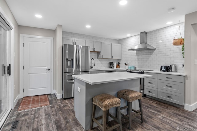 8060 Stuart Pl, Westminster, CO 80031 - kitchen with stainless steel appliances, wall chimney range hood, gray cabinets, a kitchen breakfast bar, and tasteful backsplash